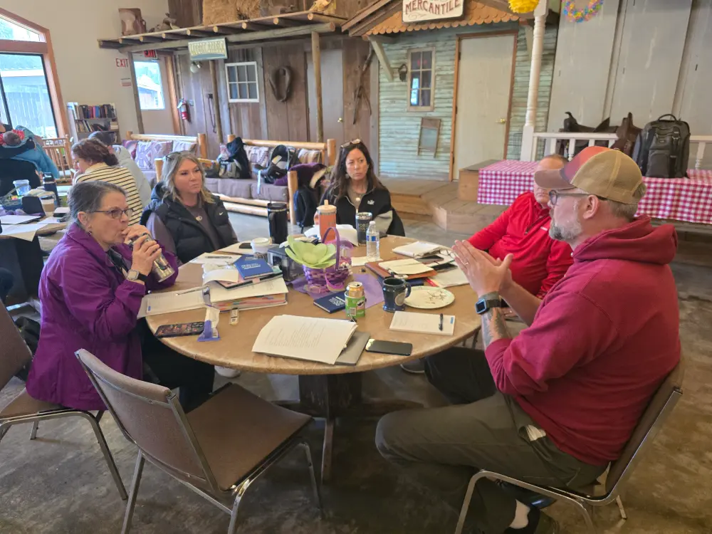 5 members and business owners of the local chamber, 3 adult females and 2 adult males, sit at a round table with materials to learn, grow and take notes at Silverton Chamber's membership retreat. Members participate in small business networking events, business networking group activities, and business network services to support local area businesses in Silverton, Oregon.